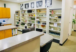 Modern dental office reception area with white counter, yellow cabinetry, and organized shelving.