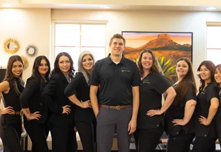 Valley Dental Care team smiling together in office wearing black uniforms