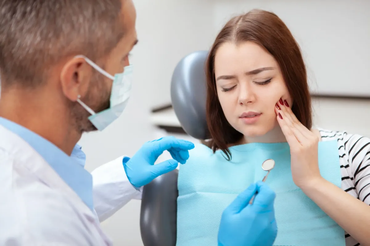 Dentist examining patient's teeth during dental checkup in clinical office setting.
